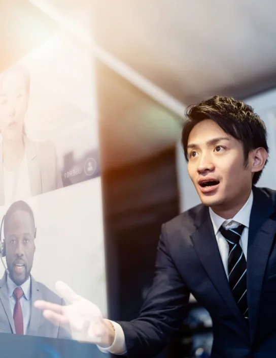 写真：男性がオンライン会議で複数の画面を見ながら話している。